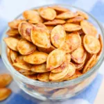 Garlic Roasted Pumpkin Seeds are displayed in a close-up shot, highlighting their crispy texture and savory seasoning.