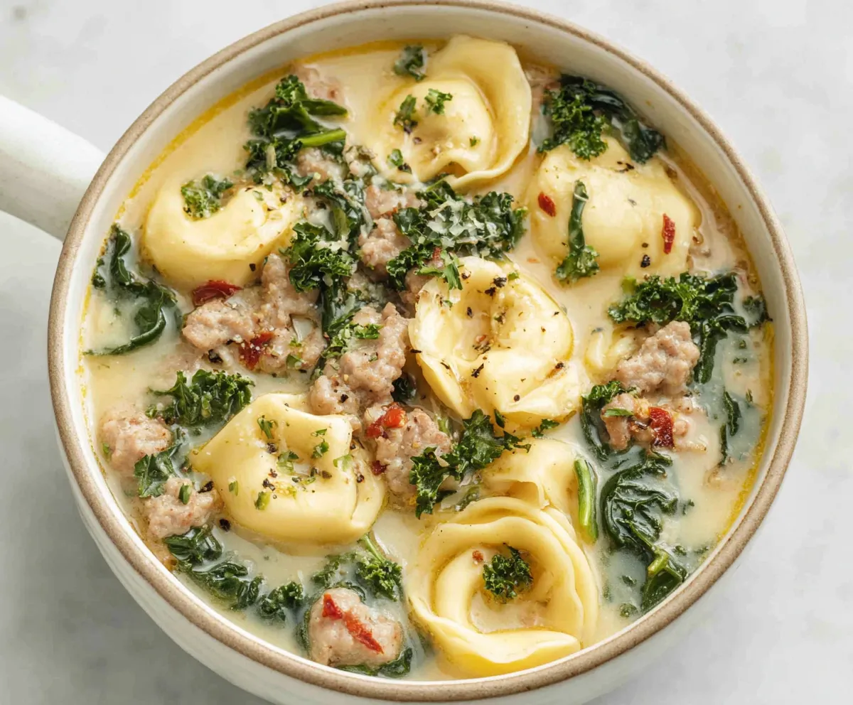 A comforting bowl of Autumn Tortellini Soup With Sausage is shown, highlighting its hearty ingredients and inviting presentation.