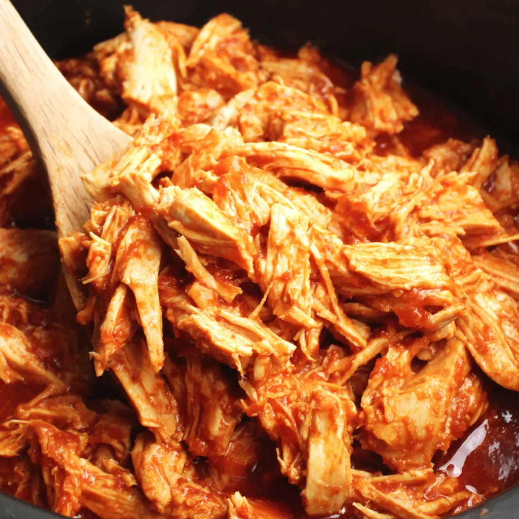 A close-up shot showcases a delicious BBQ Pulled Chicken Crockpot ready to be served.