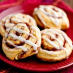 Close-up of warm, golden-brown Cinnamon Roll Cookies, showcasing their swirls and icing, for a recipe article.
