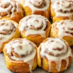 Close-up of freshly baked Pumpkin Cinnamon Roll Muffins, showcasing their swirl pattern and delicious glaze.