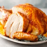 A beautifully browned Roast Turkey sits on a platter, ready to be carved and served for a festive meal.