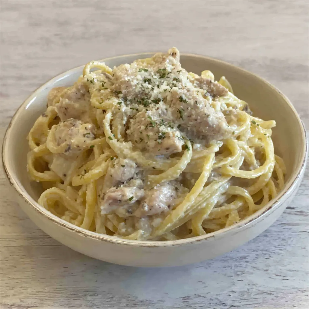 Close-up shot of a delicious plate of Creamy Chicken Alfredo, showcasing its rich sauce and tender chicken.