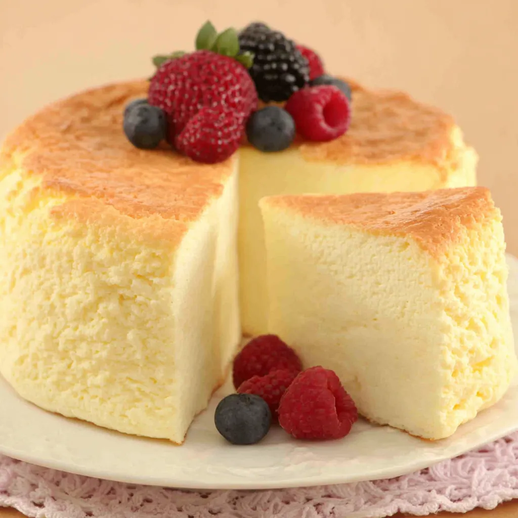 Fluffy and delicious Japanese Cotton Cheesecake sits on a white plate, showcasing its light and airy texture.