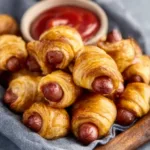 Golden-brown Pigs in a Blanket are displayed as the featured image for the recipe article.